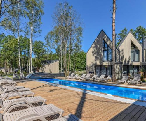 a swimming pool with lounge chairs next to a house at Žalia kopa House in Palanga