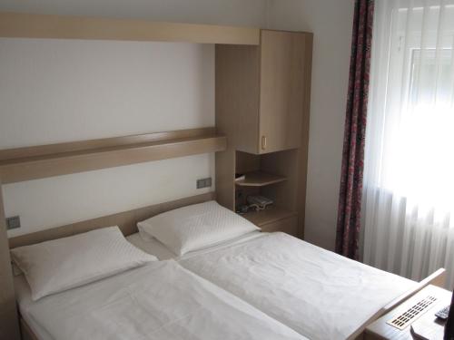 a bedroom with a bed and a telephone and a window at Hotel Maifelder Hof in Mayen