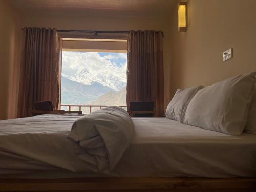 a bedroom with a bed with a view of a mountain at applegardenhunza in Alīābād