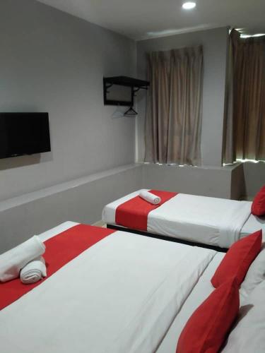 two beds with red and white sheets in a room at HOTEL AVATARR in Batu Caves