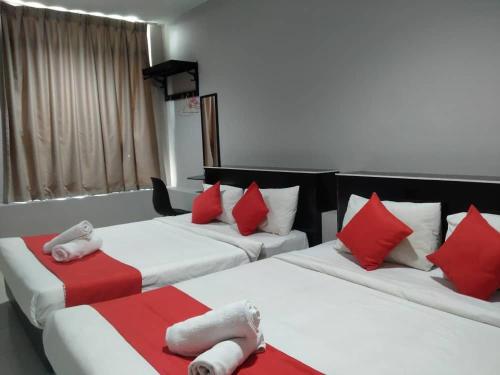 two beds in a room with red and white pillows at HOTEL AVATARR in Batu Caves