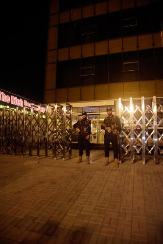 two men standing in front of a building at night at The Rich Hotel & Apartments in Lahore