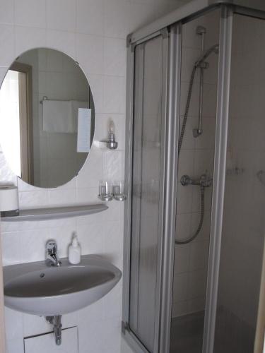 La salle de bains est pourvue d'un lavabo et d'une douche avec un miroir. dans l'établissement Hotel Maifelder Hof, à Mayen