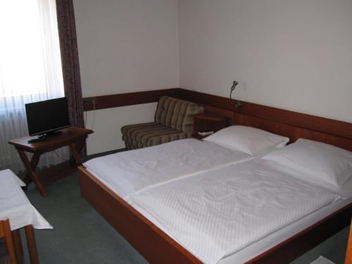 a bedroom with a bed and a chair and a desk at Hotel Maifelder Hof in Mayen