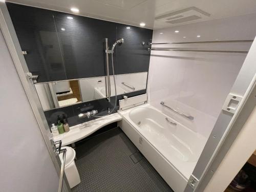 een badkamer met een bad, een wastafel en een douche bij WOLF PACK apartment 1002 in Osaka