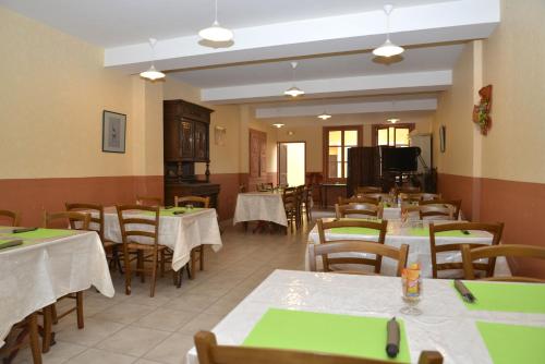 a dining room with tables and chairs and a television at Hôtel Des Arceaux in Saint-Sever