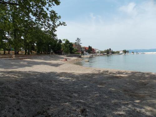 a beach with people sitting on the sand and the water at Apartment Sladić in Njivice