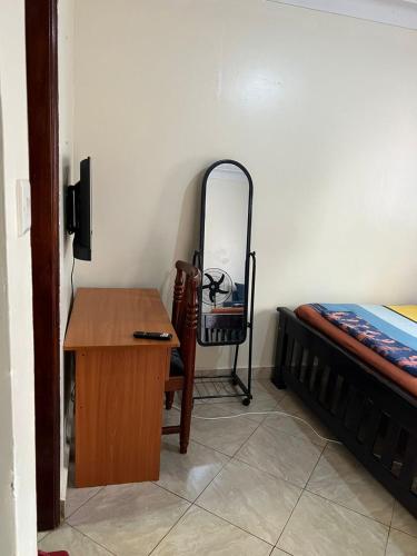 a bedroom with a desk and a bed and a mirror at Pearl suites - Bukoto in Kampala