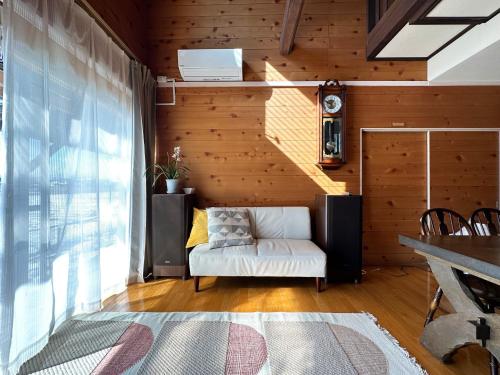 een woonkamer met een witte bank en houten wanden bij guest house Kuu - Vacation STAY 46399v in Takashima