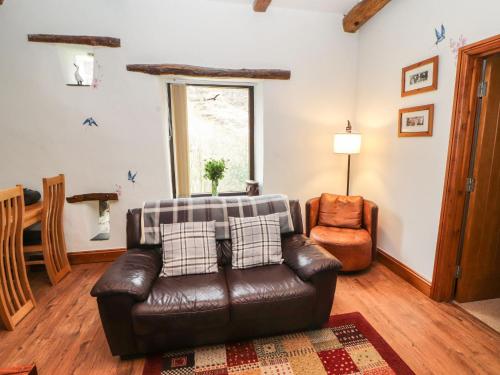 a living room with a leather couch and a chair at The Hayloft in Keswick