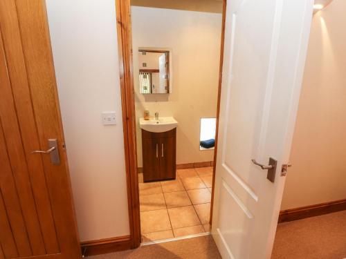 a bathroom with a sink and a mirror and a door at The Hayloft in Keswick