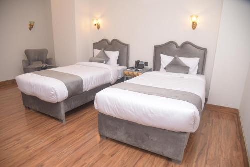 two beds in a room with wooden floors at The Rich Hotel & Apartments in Lahore