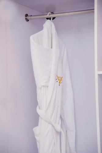 a white robe hanging on a towel rack at The Rich Hotel & Apartments in Lahore