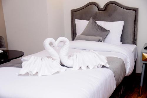 two white swans are sitting on top of a bed at The Rich Hotel & Apartments in Lahore