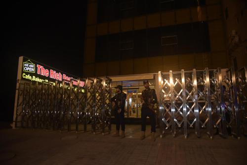 a group of men standing next to a fence at night at The Rich Hotel & Apartments in Lahore