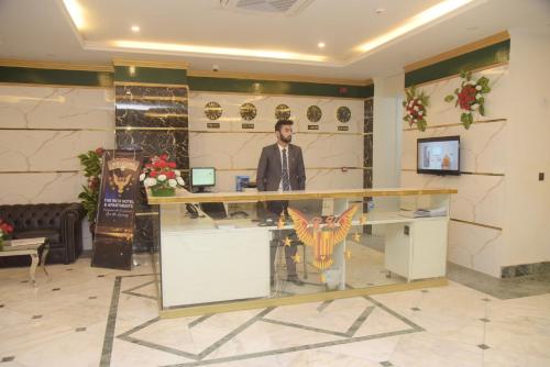 a man standing at a counter in a lobby at The Rich Hotel & Apartments in Lahore