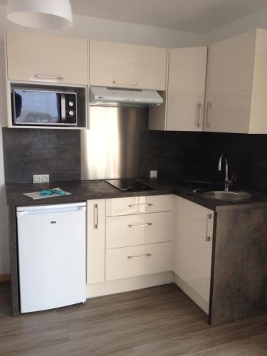 a kitchen with white cabinets and a sink and a microwave at Studio Hesperides in Balaruc-les-Bains