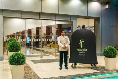 un hombre está de pie junto a una gran escultura en Holiday Inn Riyadh Al Qasr, an IHG Hotel en Riad