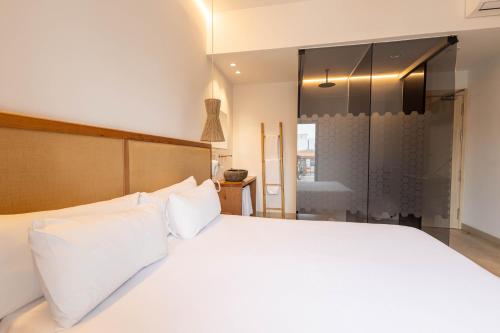 a bedroom with a large white bed and a shower at Play Hotel Ibiza - Adults Only in Ibiza Town