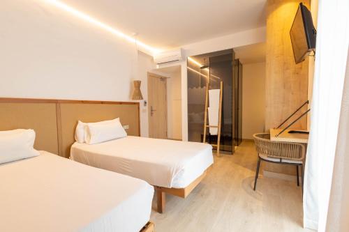 a hotel room with two beds and a desk at Play Hotel Ibiza - Adults Only in Ibiza Town