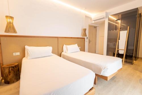 two beds in a room with white sheets at Play Hotel Ibiza - Adults Only in Ibiza Town