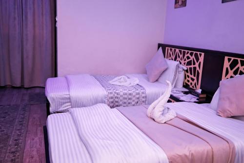two beds in a room with purple and white at رويال ابو الوفا in Suwhaj