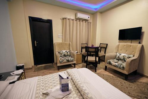 a bedroom with a bed and two chairs and a tv at رويال ابو الوفا in Suwhaj