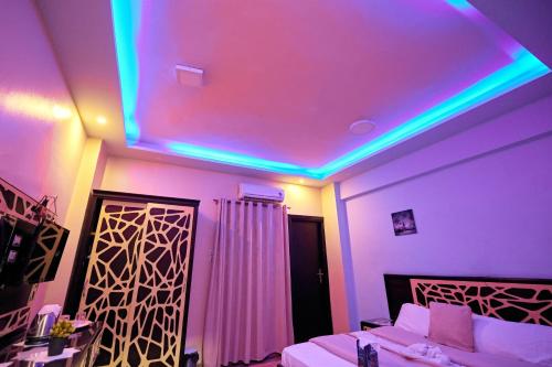 a bedroom with purple and blue lights on the ceiling at رويال ابو الوفا in Suwhaj