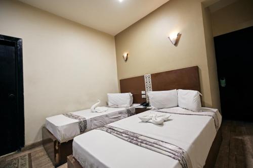 a bedroom with two beds with white sheets at رويال ابو الوفا in Suwhaj