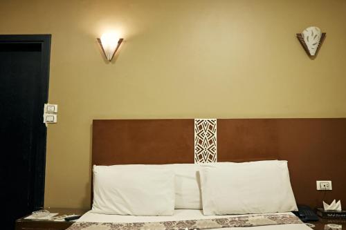 a bedroom with a bed with a brown headboard and white pillows at رويال ابو الوفا in Suwhaj