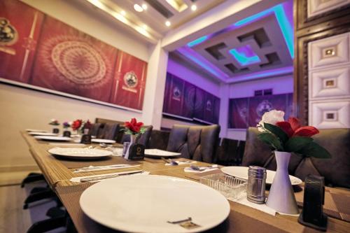 a long table in a restaurant with white plates and flowers at رويال ابو الوفا in Suwhaj