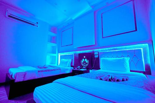two beds in a room with blue lights at رويال ابو الوفا in Suwhaj
