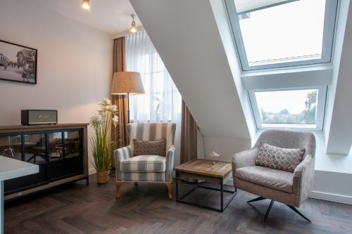 a living room with two chairs and a tv at Hotel Achterum Greetsiel in Greetsiel