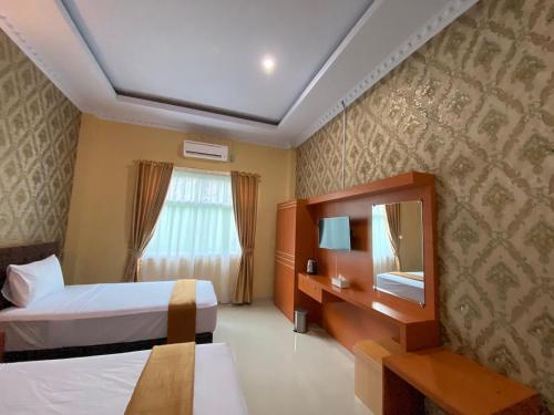 a hotel room with two beds and a mirror at Wisma Jannatun Naim Lampung in Lampung