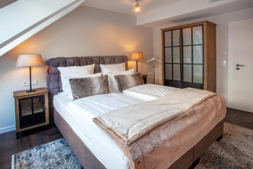 ein Schlafzimmer mit einem großen Bett mit weißer Bettwäsche und Kissen in der Unterkunft Hotel Achterum Greetsiel in Greetsiel