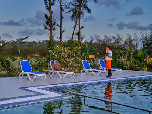 a man is standing next to a swimming pool at Zone Connect by The Park Port Blair in Port Blair
