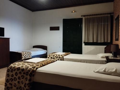 a hotel room with three beds with leopard print sheets at Paradise Studios in Kato Loutraki