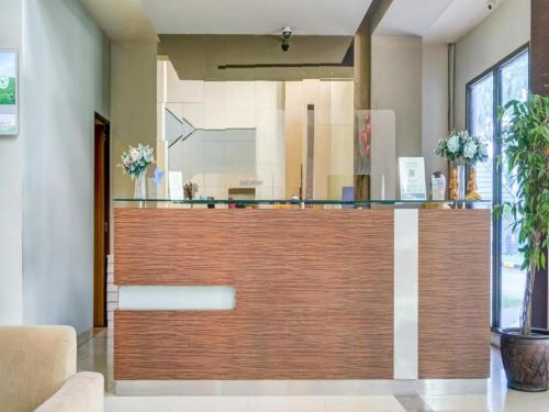 a lobby with a wooden reception desk with a counter top at Grand Cikarang Hotel in Tegalgede
