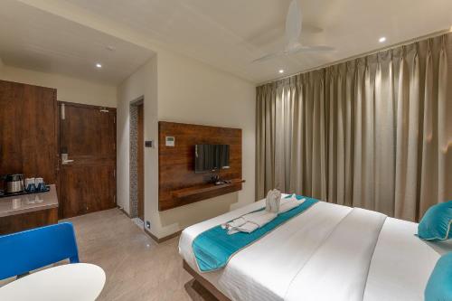 una camera con un grande letto e una televisione di Hotel Devgiri a Kolhapur