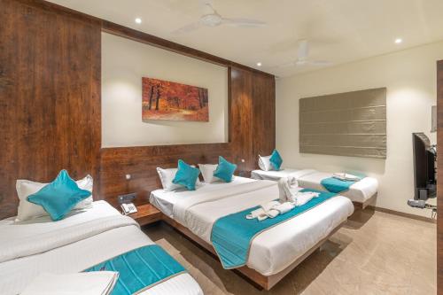 戈爾哈布爾的住宿－Hotel Devgiri，带3张床和蓝色及白色枕头的客房