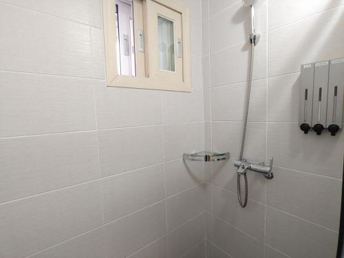 a bathroom with a shower with a window at Eutteum-won Pension in Jeju