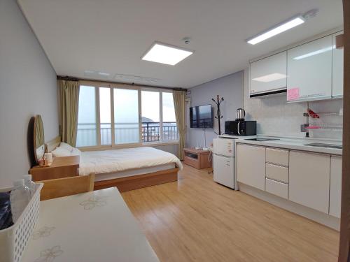 a bedroom with a bed and a kitchen with a sink at Eutteum-won Pension in Jeju
