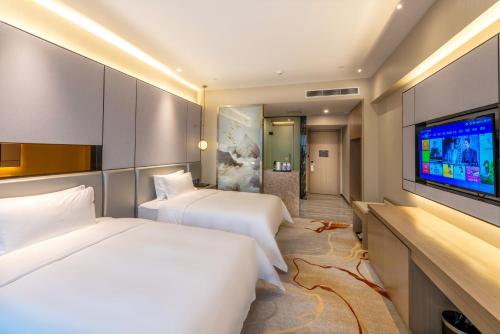 a hotel room with two beds and a flat screen tv at Qingyuan Argyle Hotel in Qingyuan