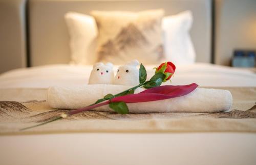 a couple of towels on a bed with a rose at Qingyuan Argyle Hotel in Qingyuan