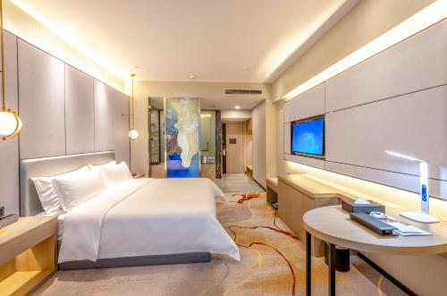 a bedroom with a bed and a desk and a tv at Qingyuan Argyle Hotel in Qingyuan