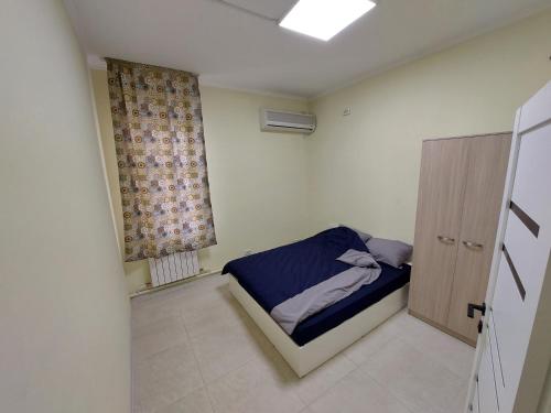 a small bedroom with a bed and a window at Check Inn Hostel in Almaty