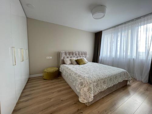 a bedroom with a bed and a large window at Apartamentai 128 in Panevėžys
