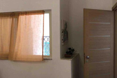 een kamer met een deur en een raam met een gordijn bij Bilocale finemente ristrutturato in Letojanni