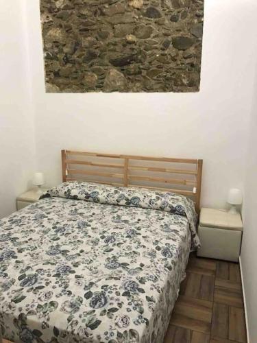 een slaapkamer met een bed en een stenen muur bij Bilocale finemente ristrutturato in Letojanni