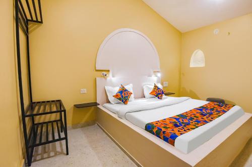 a bedroom with a large bed with an arched window at FabEscape Kautilyaa Resort With Swimming Pool 